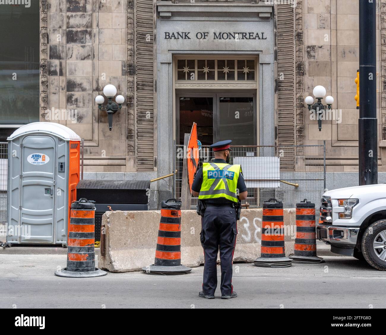 Un agent de police qui sert dans un chantier de construction de la rue Yonge, dans le district du centre-ville de Toronto, au Canada. Un ancien bâtiment de la Banque de Montréal est vu dans Banque D'Images