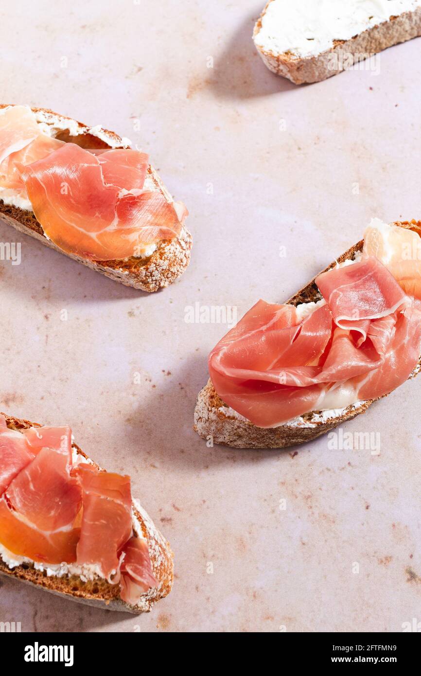 Tranches de baguette fraîche nappées de fromage à la crème fouettée et de jambon Serrano. Banque D'Images