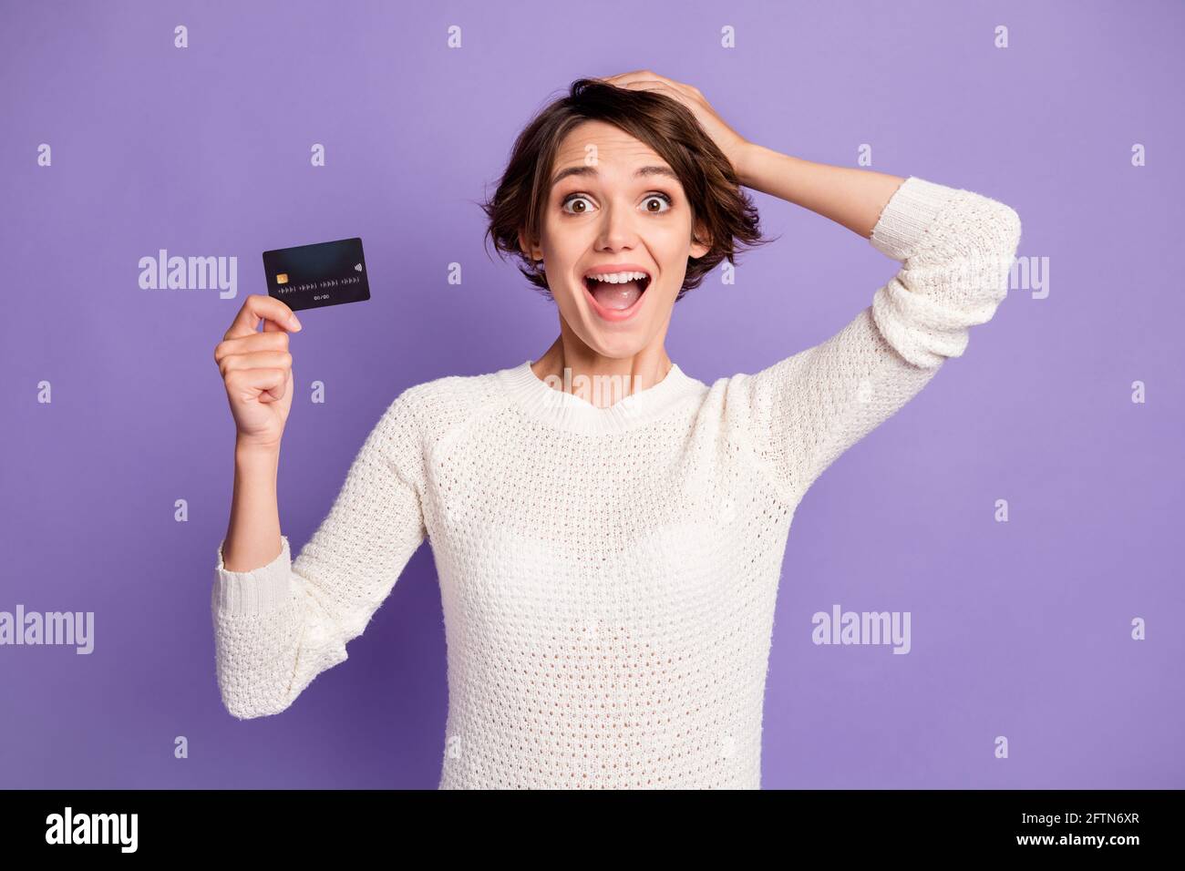 Photo portrait de femme pigiste impressionnée avec le plastique de débit carte en contact avec la tête isolée sur fond violet pastel Banque D'Images