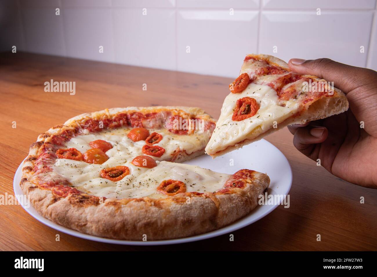 Tranche de pizza levée d'une main. Photo gastronomique Banque D'Images
