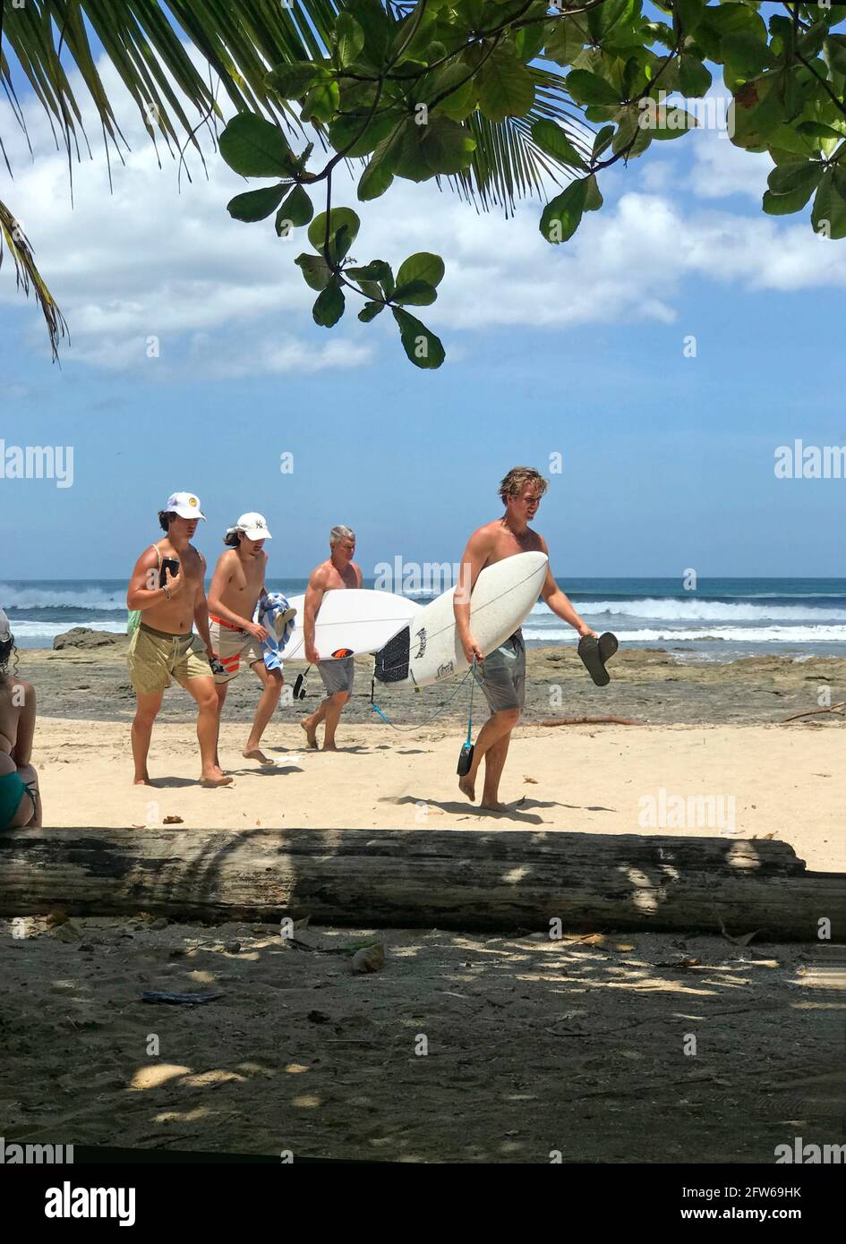 Les surfeurs retournent à la plage depuis l'océan Pacicif à Tamarindo, au Costa Rica Banque D'Images