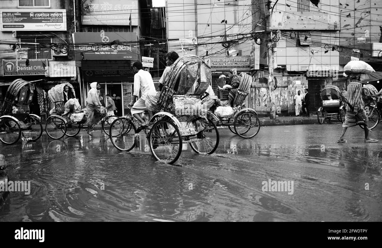 Des rickshaws à vélo traversent des rues inondées à Dhaka, au Bangladesh. Banque D'Images