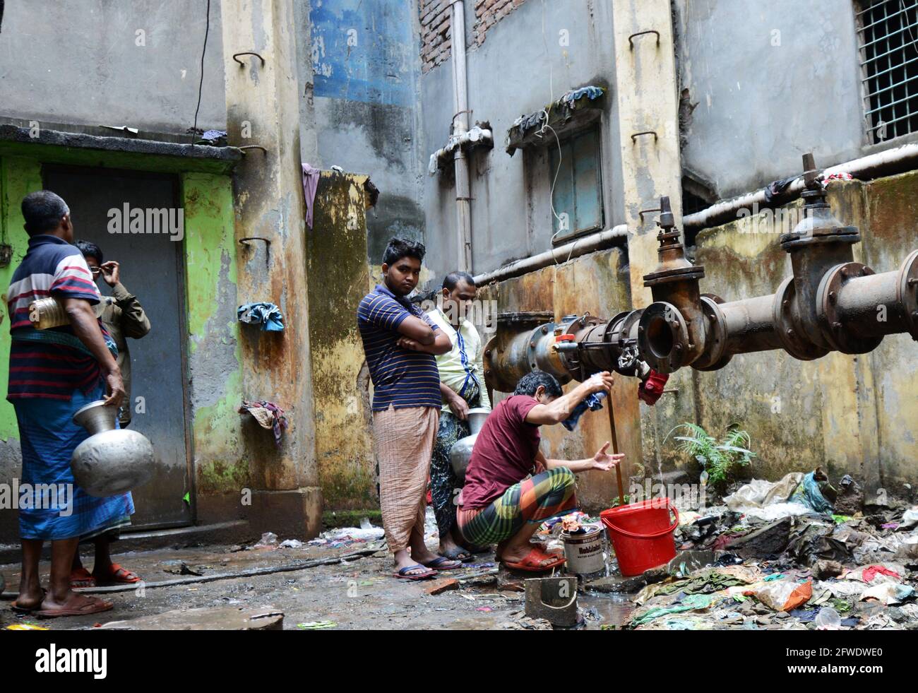 Collecte de l'eau d'un tuyau qui fuit à Dhaka, au Bangladesh. Banque D'Images