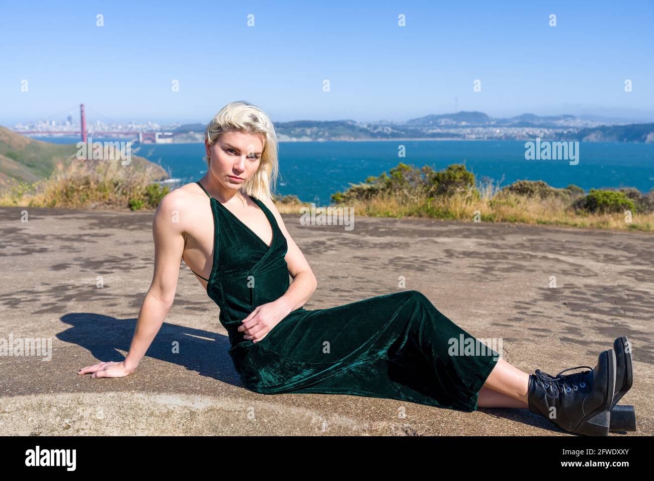 Mode dans des endroits inhabituels, femme en robe pleine longueur debout dans les ruines de la batterie d'arme à feu Banque D'Images