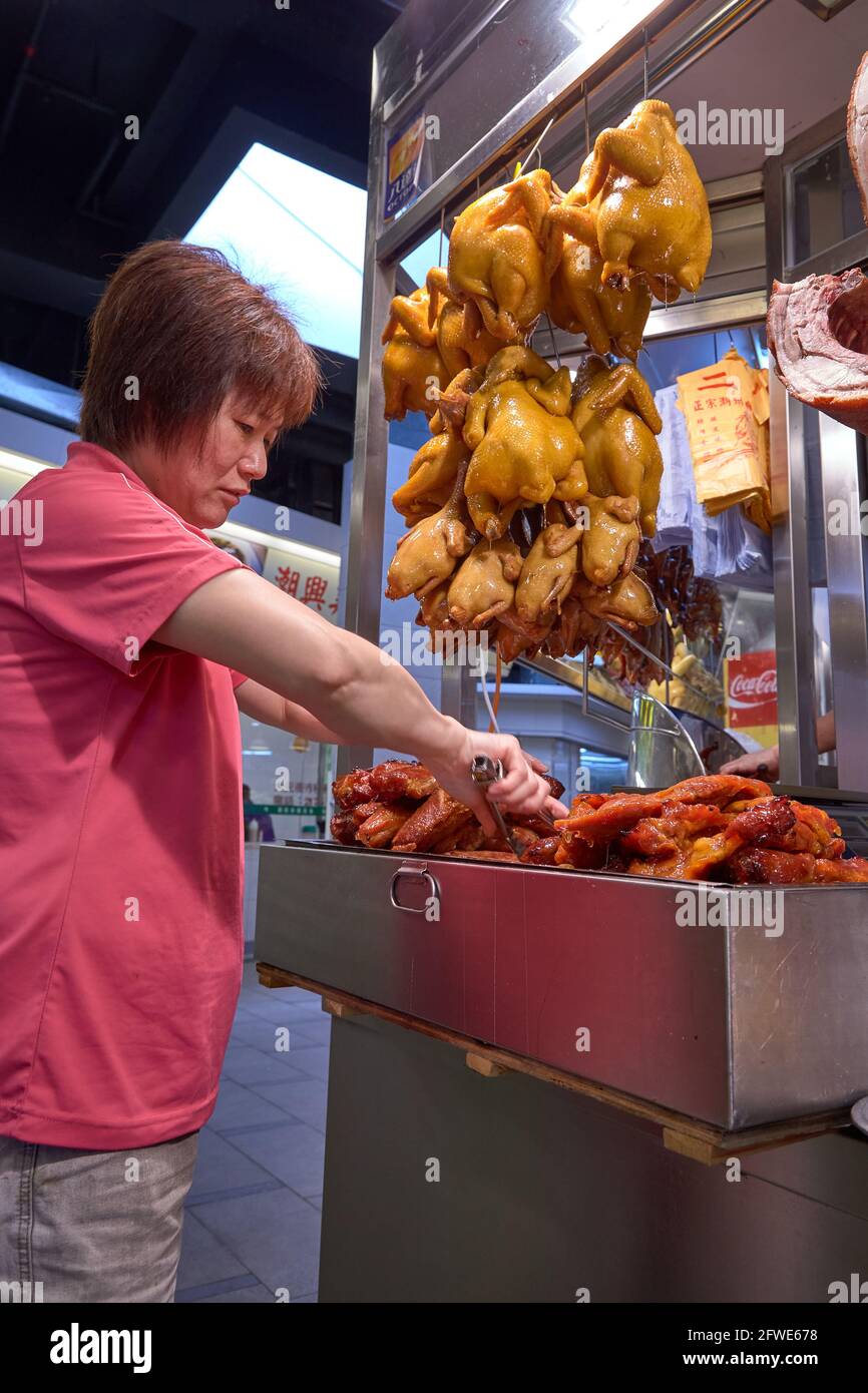 Un commerçant prépare le char siu ou le rôti de porc pour son service de boîte à lunch à son étal du marché de Tai Yuen. Banque D'Images