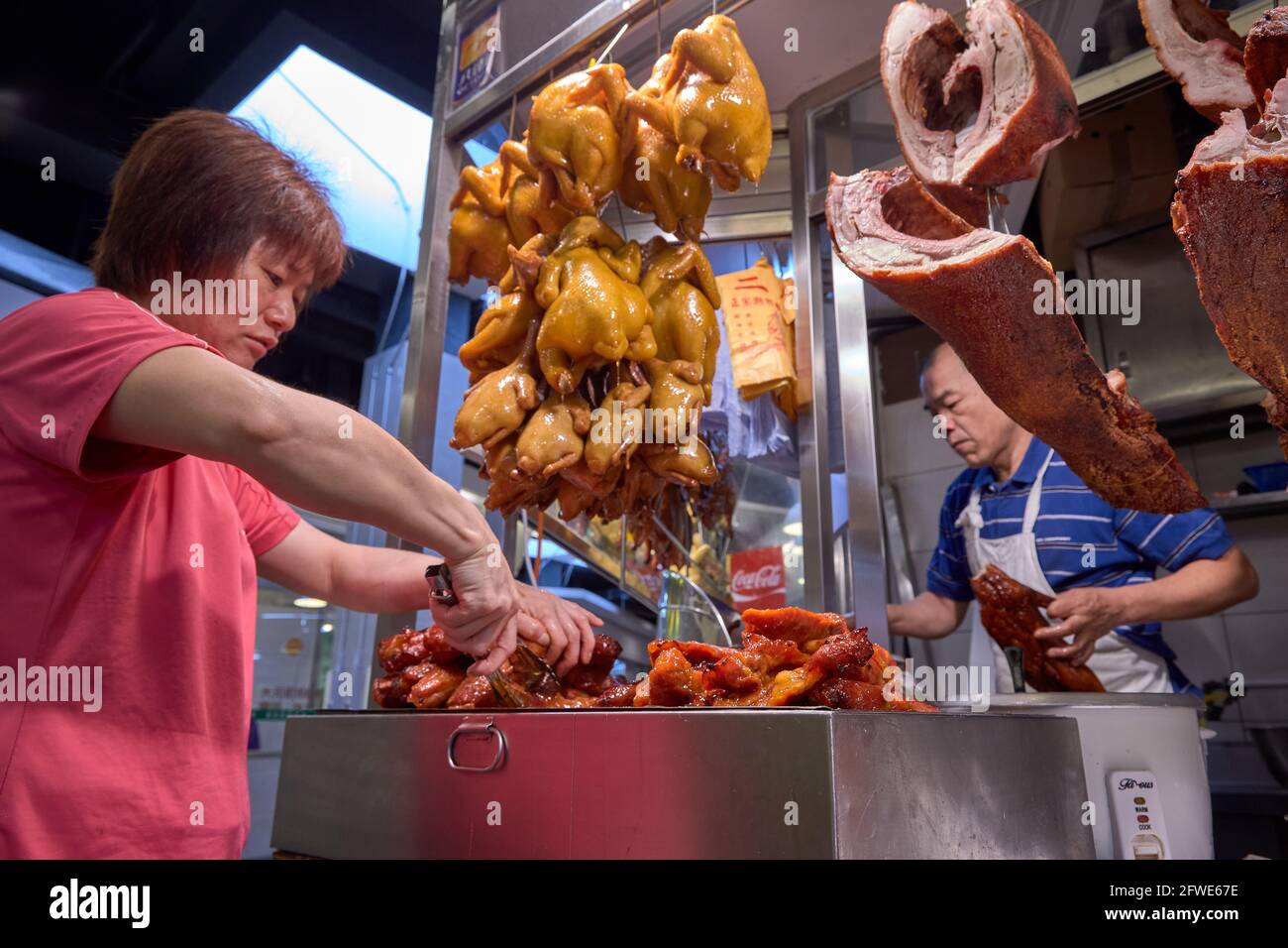 Un commerçant prépare le char siu ou le rôti de porc pour son service de boîte à lunch à son étal du marché de Tai Yuen. Banque D'Images