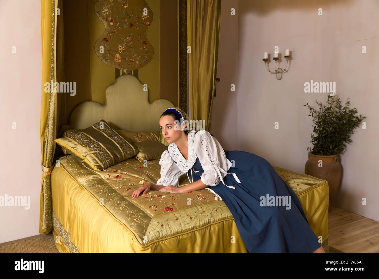 Dutch Master portrait de style d'une belle jeune femme en costume renaissance authentique allongé sur un luxueux lit à baldaquin antique dans une chambre d'or d'un Banque D'Images