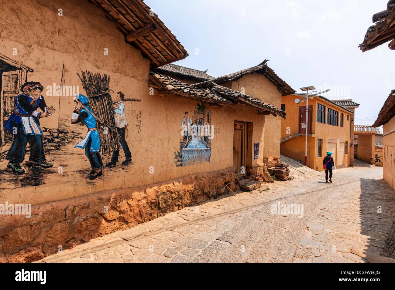 25 mars 2021 - Mile, Chine: Womand vêtu d'une tenue traditionnelle de la minorité Keyi marchant dans un village isolé Banque D'Images
