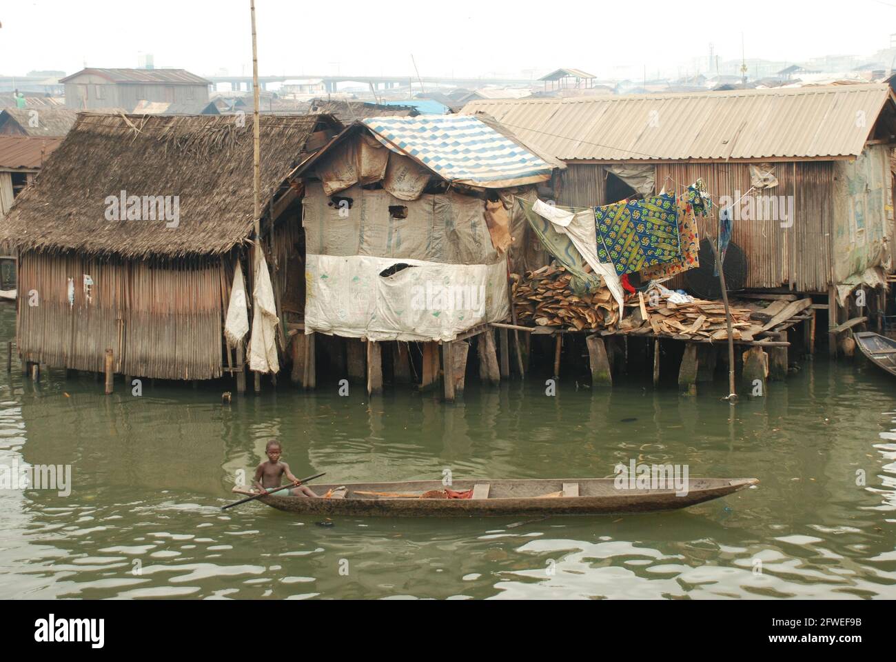 Un garçon pagayant un canoë à Makoko Slum, Lagos, Nigeria. Banque D'Images