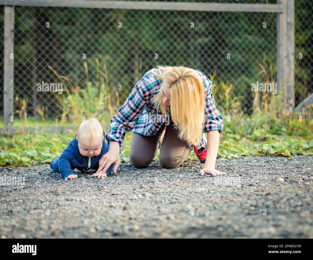 Maman joue avec l'enfant assis sur le trottoir. Famille à pied. Banque D'Images