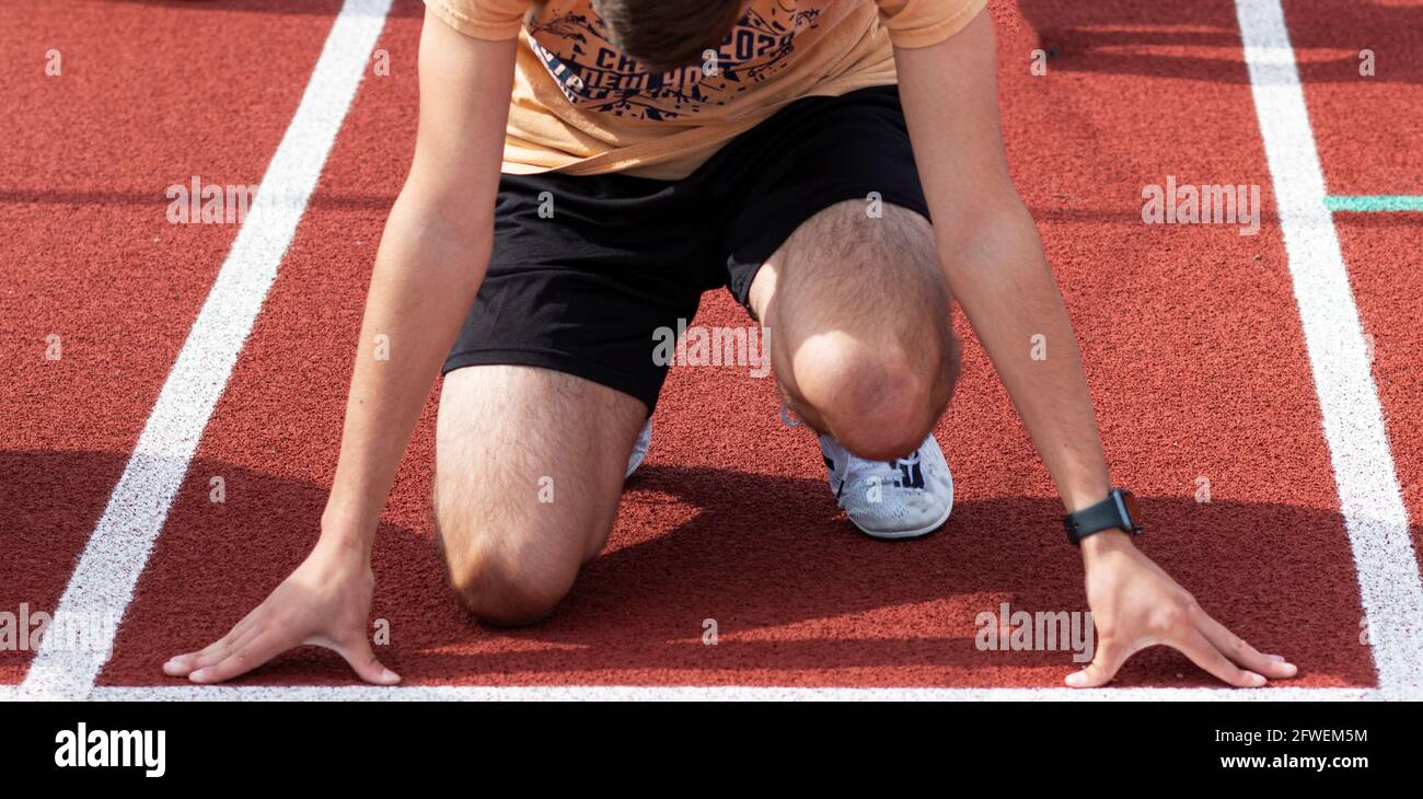 Vue de face d'un sprinter d'école secondaire à la ligne de départ prêt à s'entraîner à courir un sprinter dans les voies de la pratique. Banque D'Images