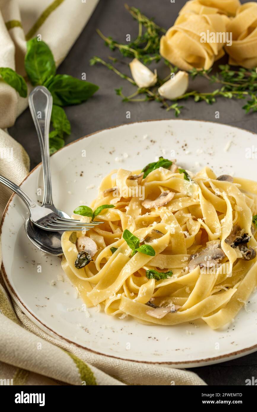 Pâtes de fettuccine aux champignons et au jambon de poulet frit dans une crème sauce au fromage sur fond de bois clair Banque D'Images