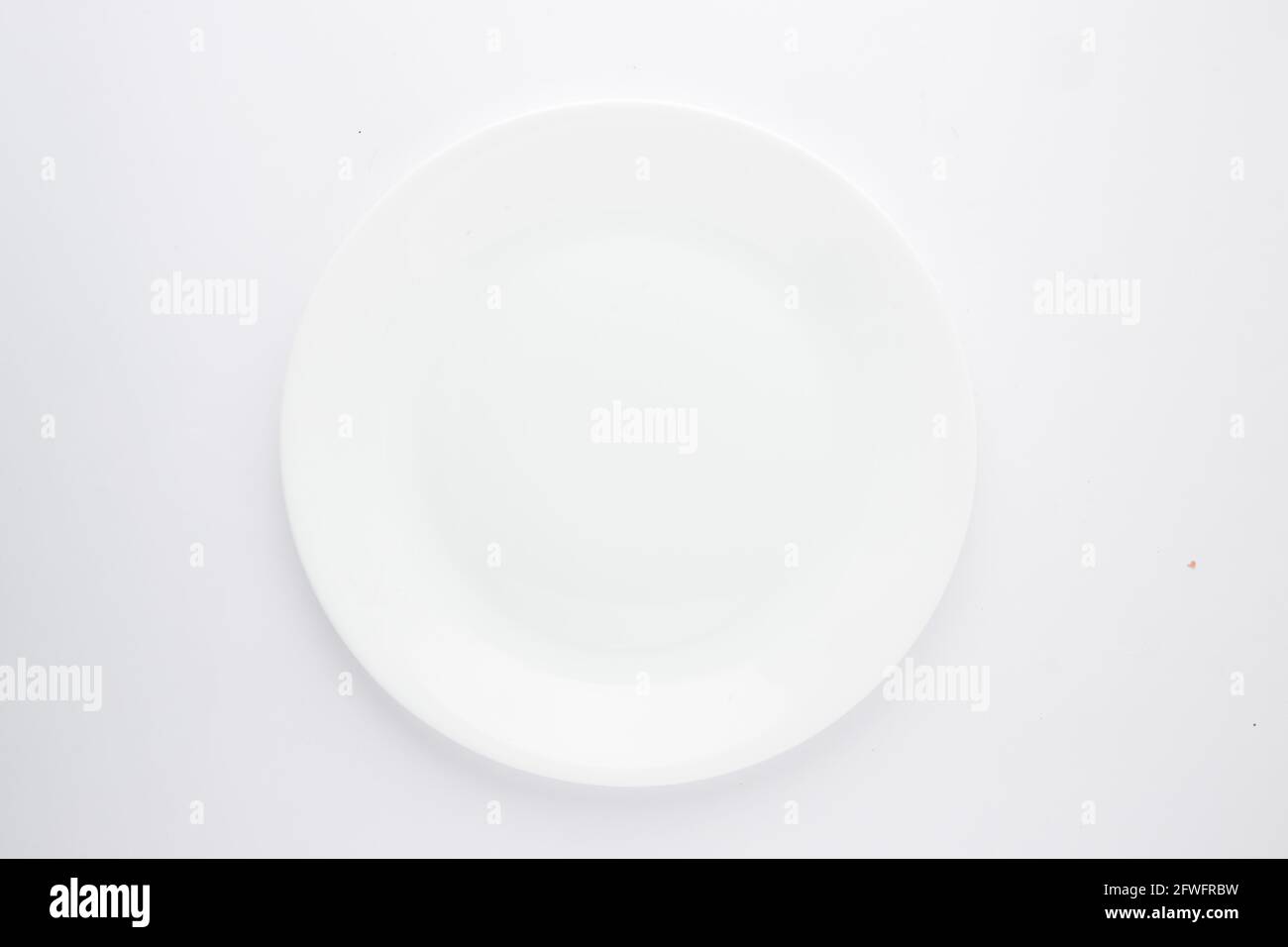 Plaque en céramique blanche, différentes formes d'une vaisselle en céramique blanche vide disposée sur un fond blanc texturé. Banque D'Images