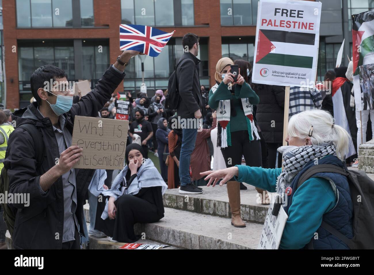 Lady fait valoir avec un protestataire qui agite Union Jack alors que les manifestants se rassemblent à Piccadilly Gardens, Manchester, Royaume-Uni. La démonstration a commencé à 12 h 22 mai 2021. La manifestation devait montrer son soutien au peuple paléopalestinien et contre la récente escalade du conflit dans la région. En Palestine, le peuple palestinien a fait face à un barrage contentant d'Israël à la suite de roquettes tirées de Gaza par le groupe militant au pouvoir du Hamas. Le cessez-le-feu a commencé au début du vendredi 20 mai 2021, mettant fin à 11 jours de combats dans lesquels plus de 250 personnes ont été tuées, la plupart à Gaza. Photo: ALVAROVELAZQUEZ/ Banque D'Images