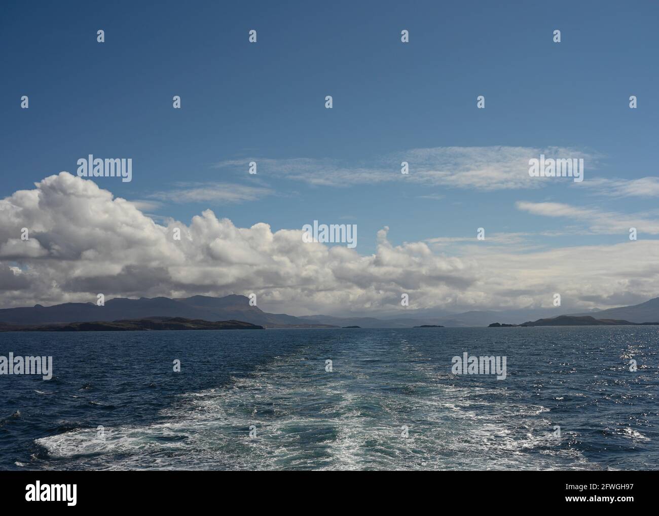 Vue depuis le ferry vers les Hébrides extérieures depuis la mer de Minch avec le bateau wake, vues lointaines sur les montagnes d'Assynt et l'Écosse continentale. Jour ensoleillé. Banque D'Images