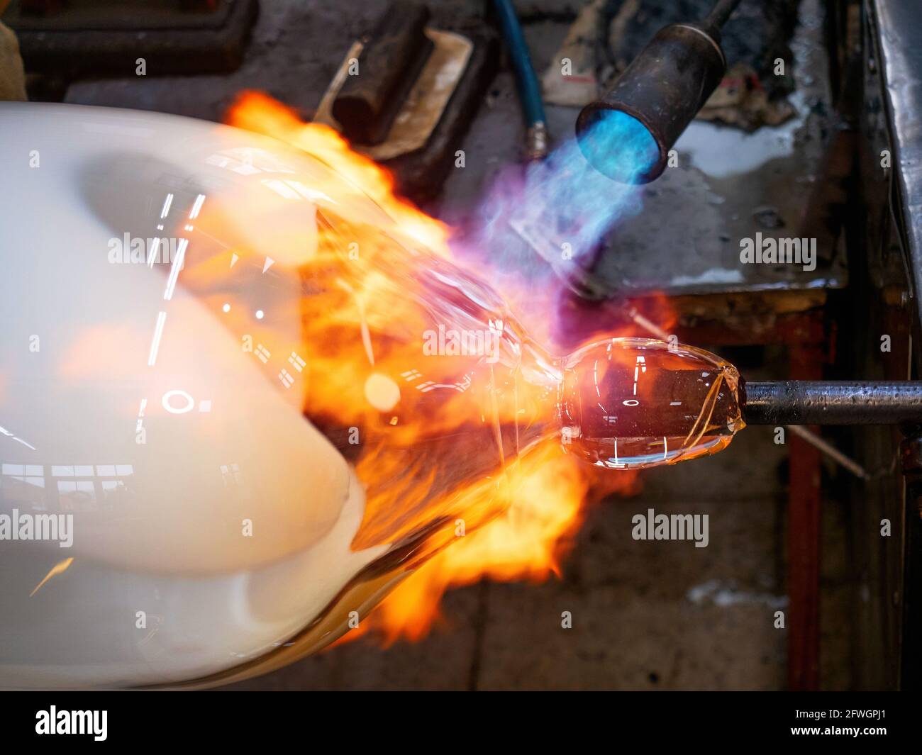 Le maître-verrier chauffe une boule de verre de feu de feu sur un tube de  verre. Verre chaud façonnant à la main dans un studio de conception de  verre à Kunratice Photo