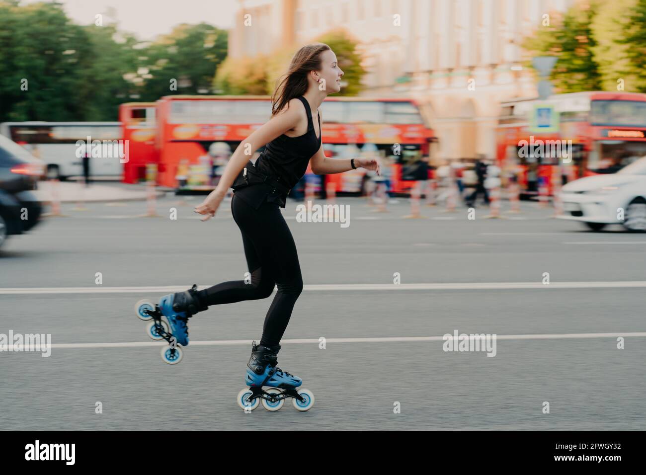 Femme européenne en bonne forme physique manèges sur rouleaux rolleblades sur les patins en ligne vêtus de vêtements actifs a le repos actif. Concept de style de vie sportif Banque D'Images