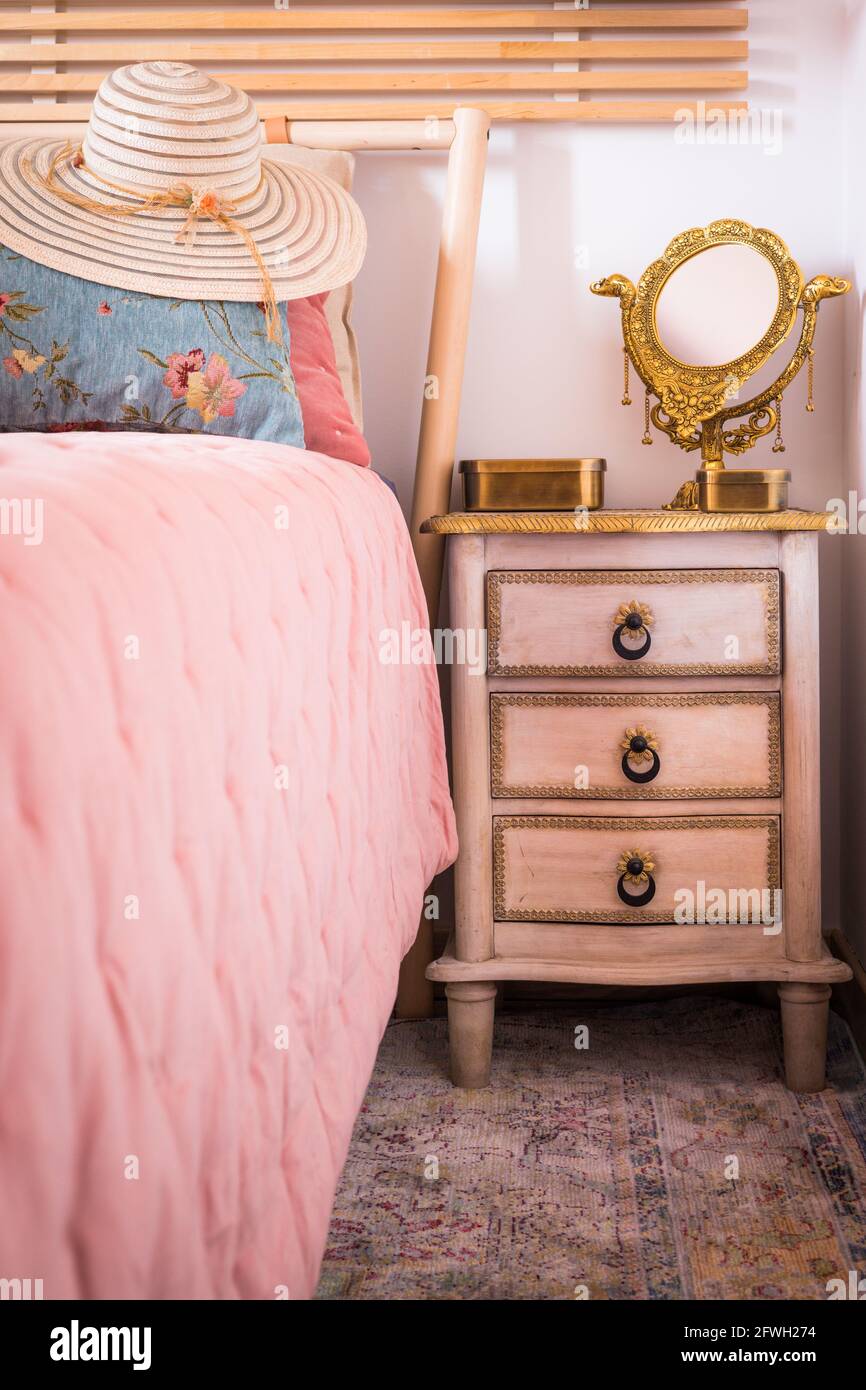 Chapeau de soleil femme élégant allongé sur le lit à côté de la table de nuit avec un miroir. Élégance dans un style féminin. Intérieur rétro Banque D'Images