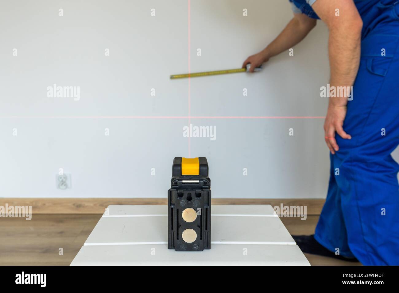 un spécialiste marque le point et le niveau sur le mur avec un laser électronique Banque D'Images