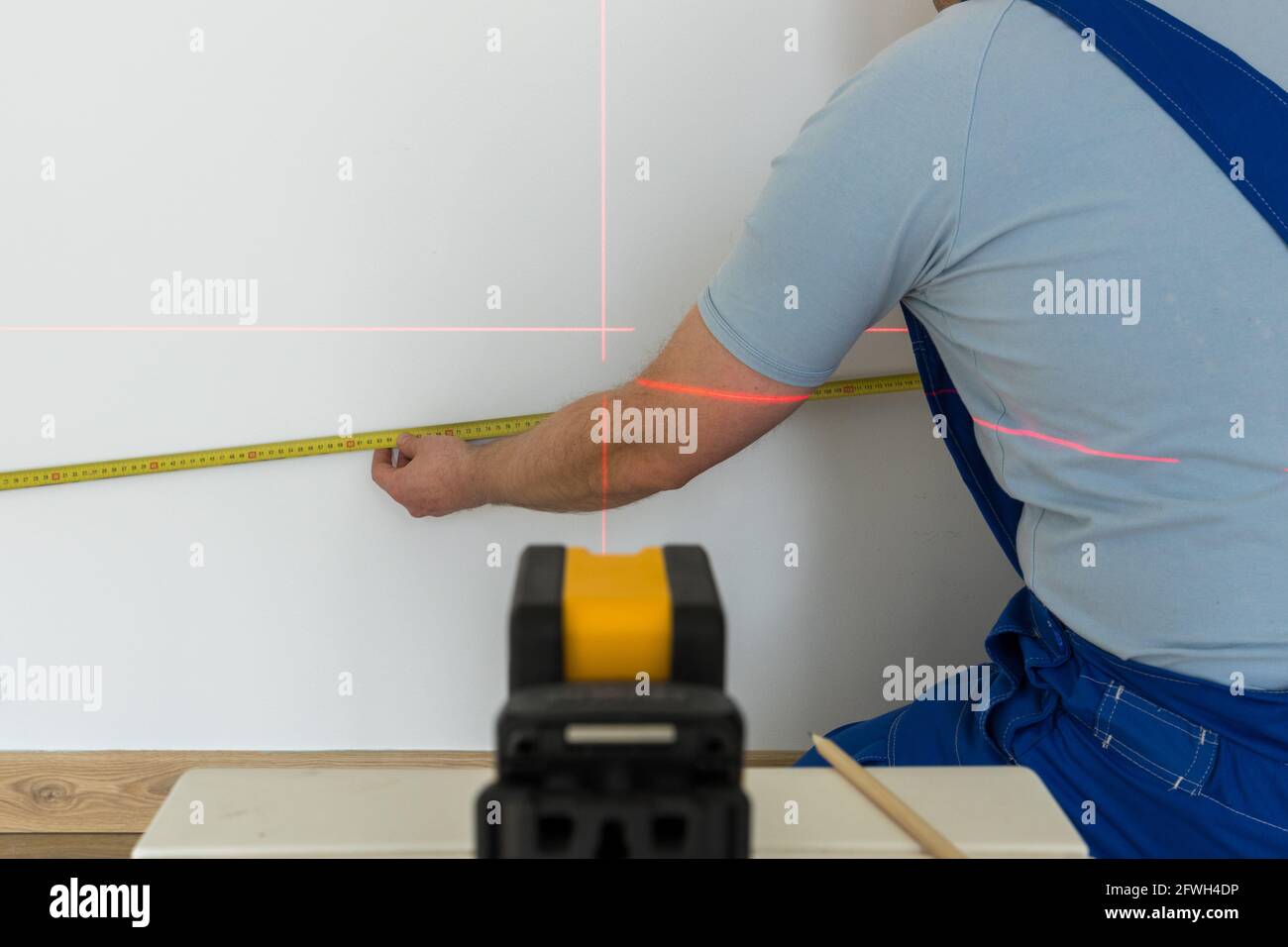 une personne qualifiée marque un point sur le mur marqué avec un laser électronique Banque D'Images