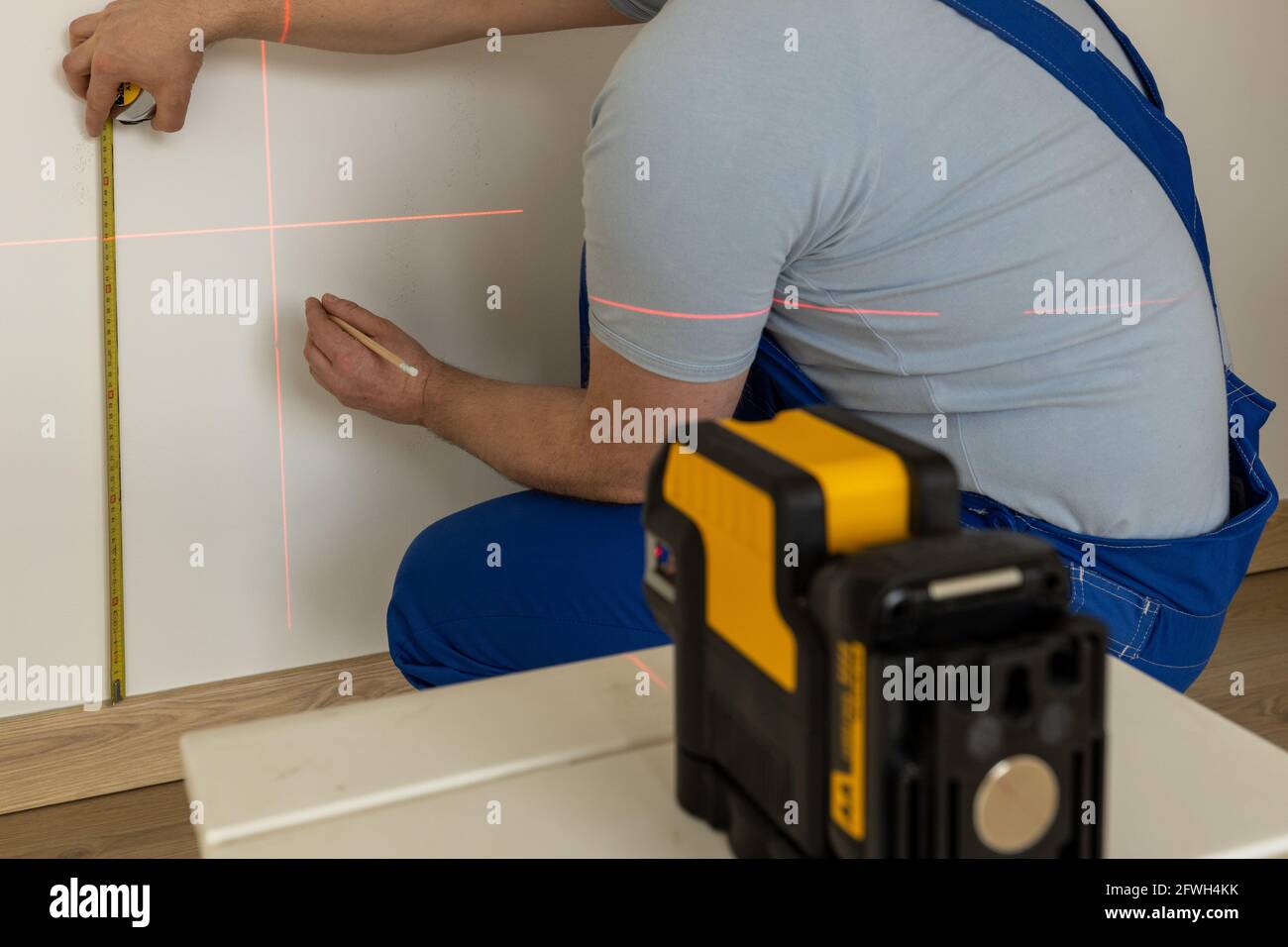 une personne qualifiée marque un point sur le mur marqué avec un laser électronique Banque D'Images