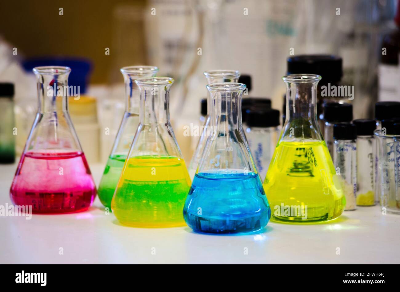 Différentes solutions colorées dans un flacon conique sur un banc dans un laboratoire de chimie avec un arrière-plan flou de photographie d'expérience de chimie organique pour backgroun Banque D'Images