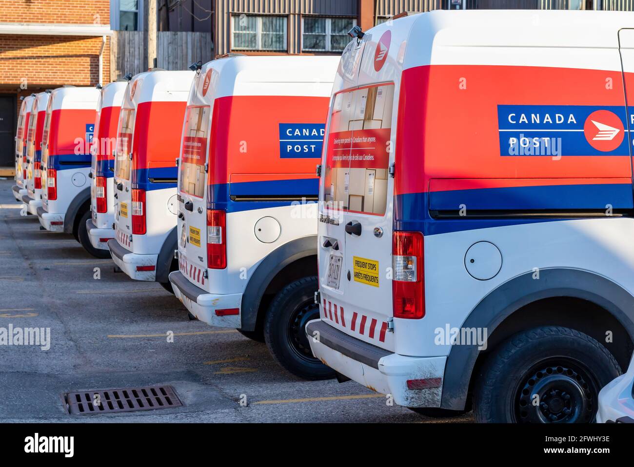 Arrière de plusieurs véhicules de postes Canada alignés dans des places de stationnement derrière un immeuble de bureaux de postes Canada. St. Thomas, Ontario, Canada. Mai 14 2021. Banque D'Images