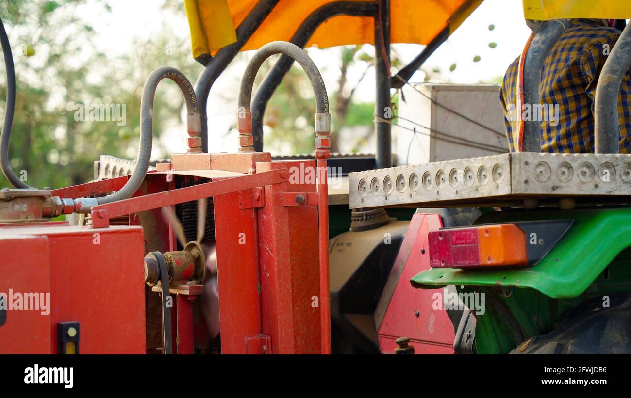 07 mai 2021 - Reengus, Sikar, Inde. Vue de dessous de la pelle hydraulique qui bascule le godet de couleur rouge chargé d'engrais organique sur fond ciel bleu nuageux Banque D'Images