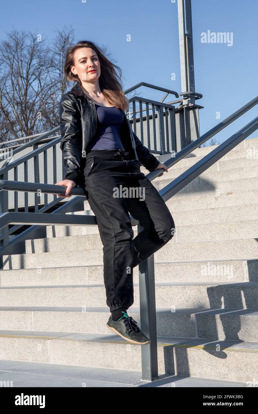 jeune femme en cuir, assise à l'extérieur sur un escalier main courante Banque D'Images