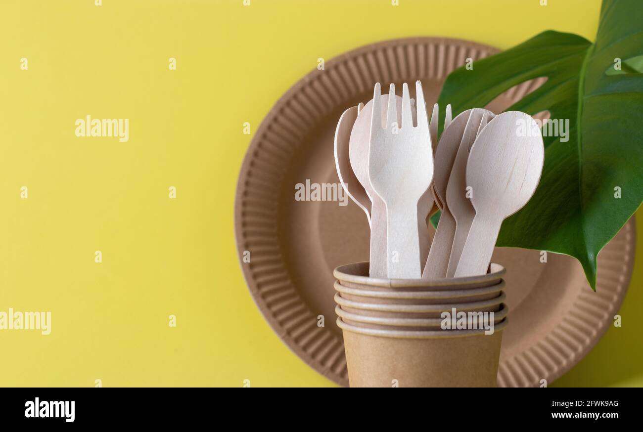 bunner vaisselle jetable écologique sur fond jaune. Fourchettes et cuillères en bois dans une tasse en papier avec assiette en papier. Aucun gaspillage Banque D'Images