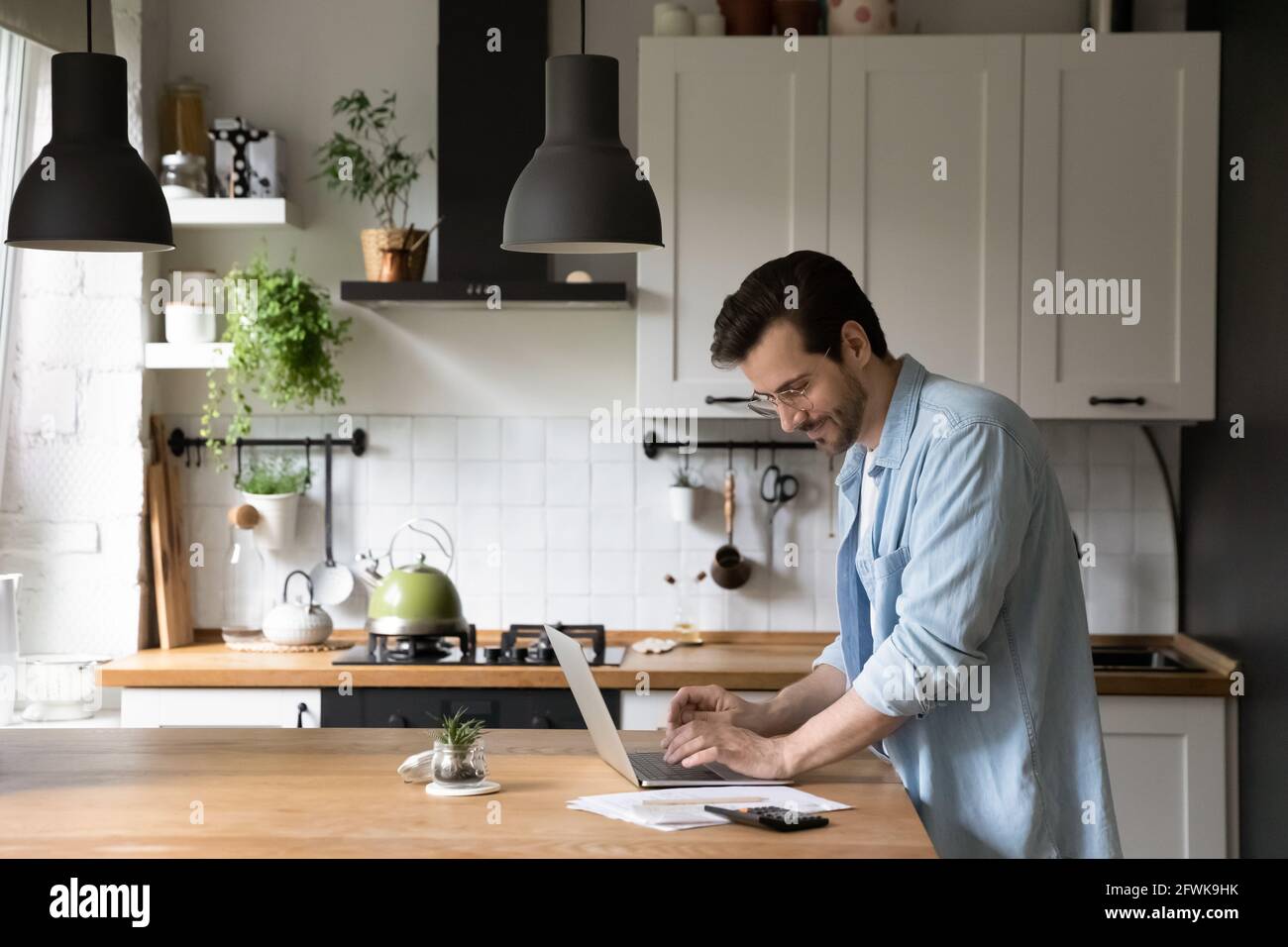 Un jeune homme heureux dans les lunettes de gestion des paiements de ménage. Banque D'Images