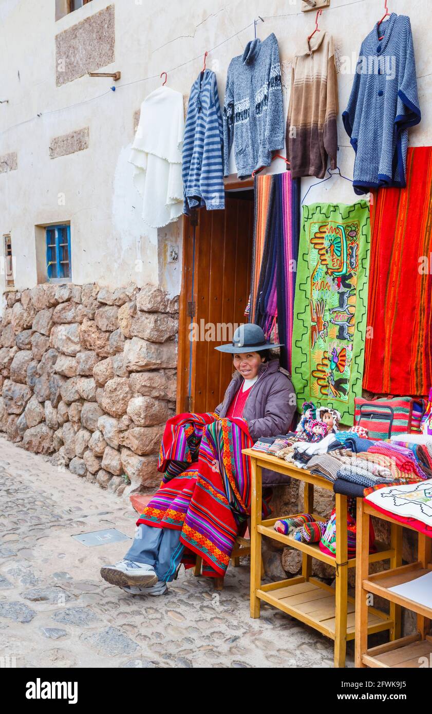 Femme quechua locale assise à l'entrée d'une boutique de souvenirs touristiques à Chinchero, un village rustique andin, Vallée Sacrée, Urubamba, Cusco, Pérou Banque D'Images