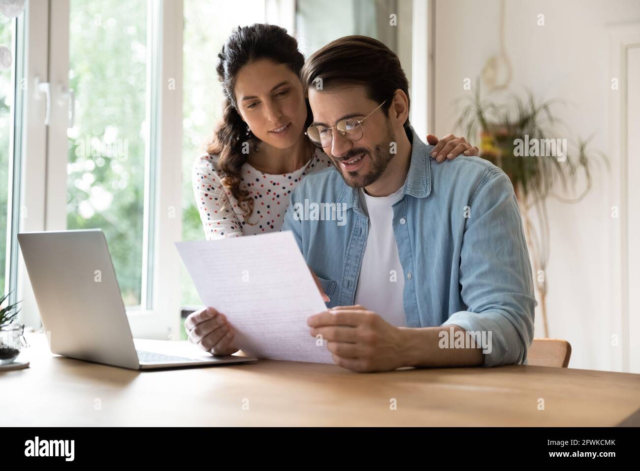 Joyeux couple affectueux de jeunes familles lisant la correspondance papier. Banque D'Images