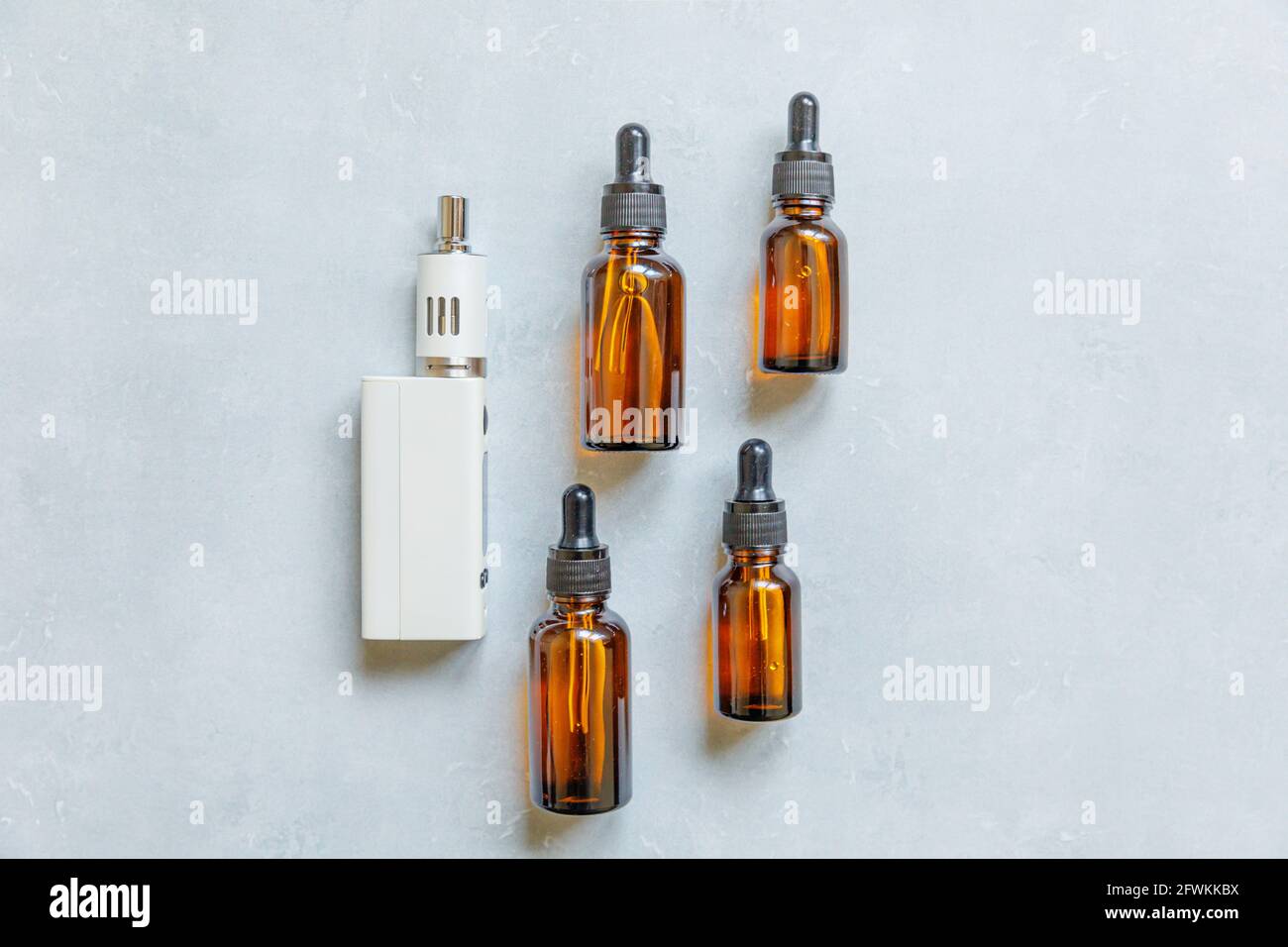 Cigarettes électroniques et bouteilles de liquide de l'appareil de Vaping sur fond gris en pierre de béton. Dispositif VAPE pour fumer de substitution. Boutique Vaping Banque D'Images