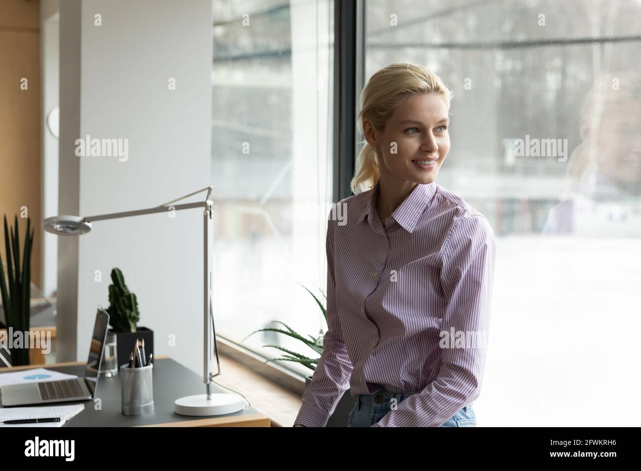 Rêveuse femme d'affaires souriante qui cherche à côté au bureau Banque D'Images