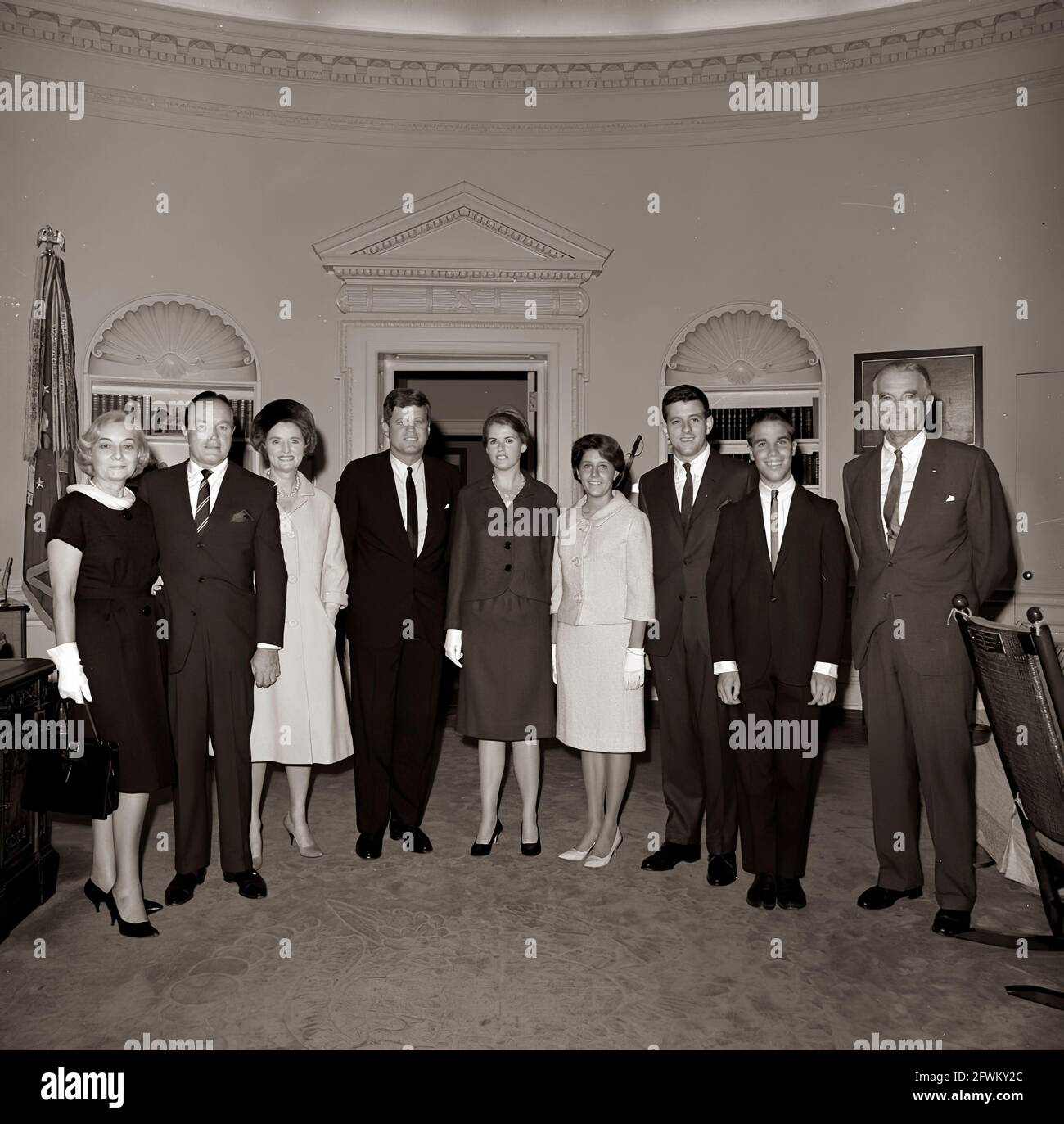 Le Président John F. Kennedy visite l'acteur et comédien Bob Hope et d'autres personnes dans le Bureau ovale de la Maison Blanche, Washington, D.C.; M. Hope s'est rendu à la Maison Blanche pour recevoir la Médaille d'or du Congrès, remise par le Président Kennedy en reconnaissance de ses services au pays en tant qu'animateur pendant la Seconde Guerre mondiale De gauche à droite : Rita Millar, épouse de Mack Millar, attaché de presse de M. Hope; M. Hope; Dolores Hope; présidente; Linda Hope; Nora Hope; Anthony Hope; William Kelly Hope; sénateur Stuart Symington (Missouri). Banque D'Images