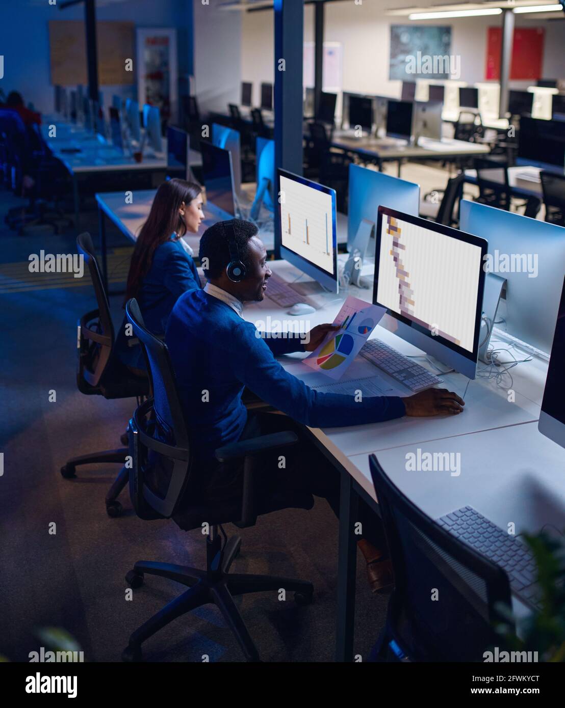 Deux directeurs travaillent dans le bureau de nuit, vue arrière Banque D'Images