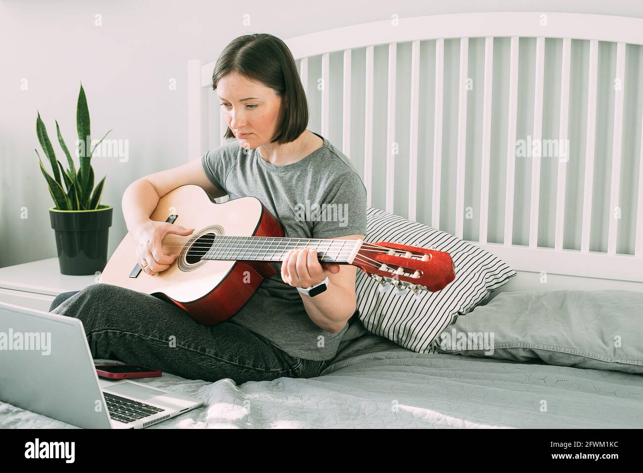 La jeune femme regarde la leçon vidéo sur la guitare à la maison. Cours de  guitare en ligne. Concept de passe-temps, activités de loisirs pendant la  quarantaine, soi-même Photo Stock - Alamy