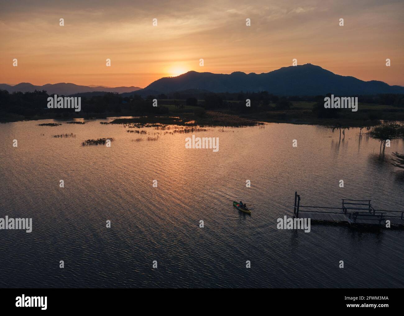 Vue aérienne des touristes pagayant en canoë sur le lac et coucher de soleil sur la montagne Banque D'Images