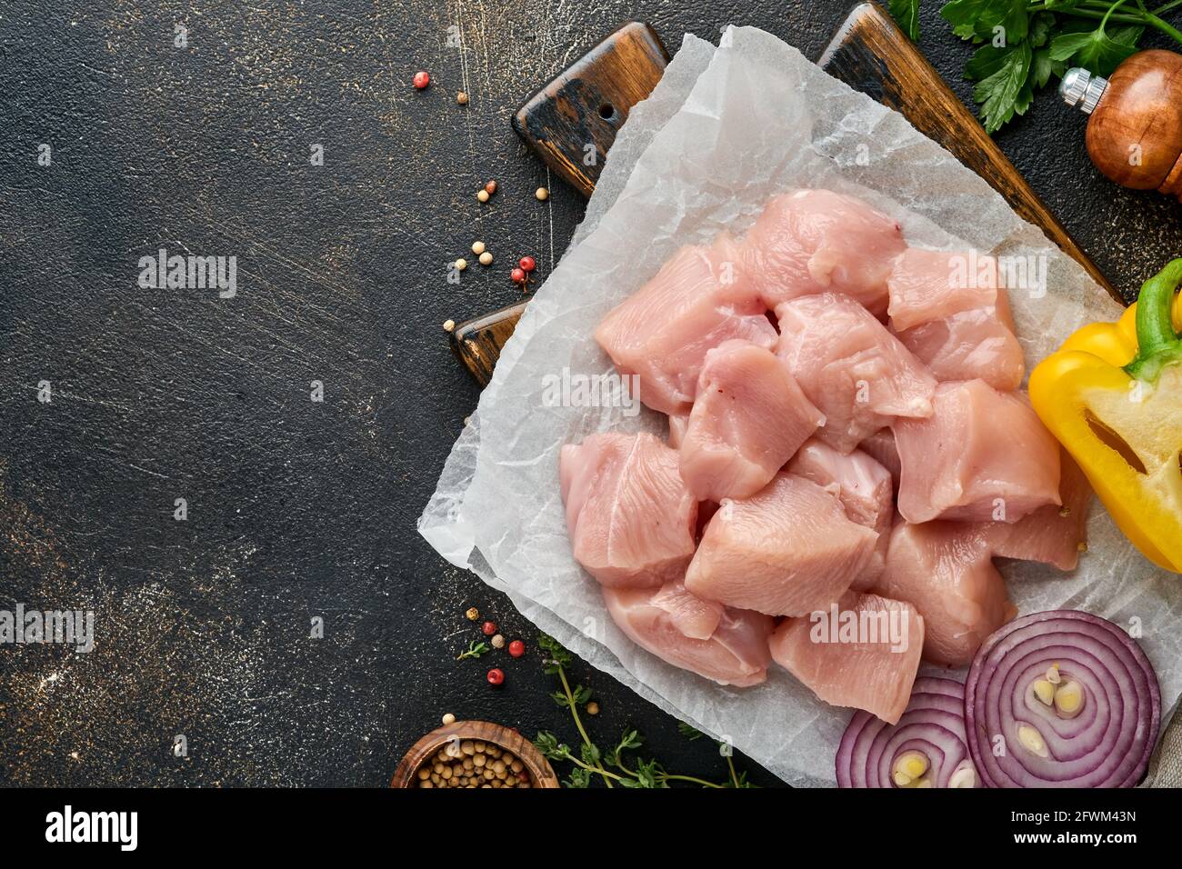 Morceaux crus ingrédients de viande de poulet sur bois, épices, herbes et légumes sur fond gris foncé. Ingrédients crus pour le goulash ou le shish keb Banque D'Images