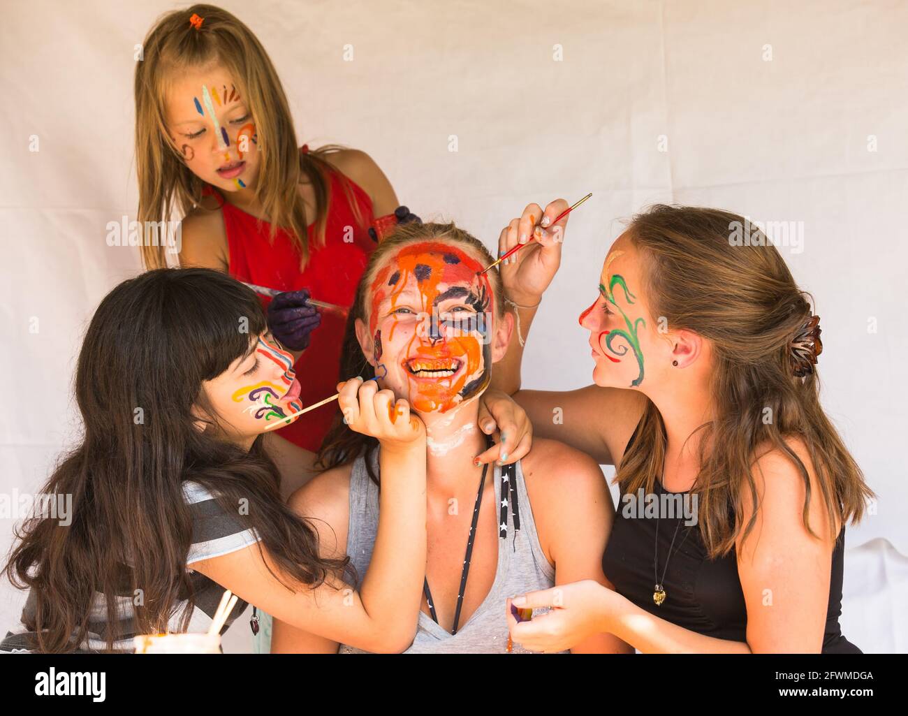 Trois petites filles jouant avec la peinture visage soeur senior. Banque D'Images