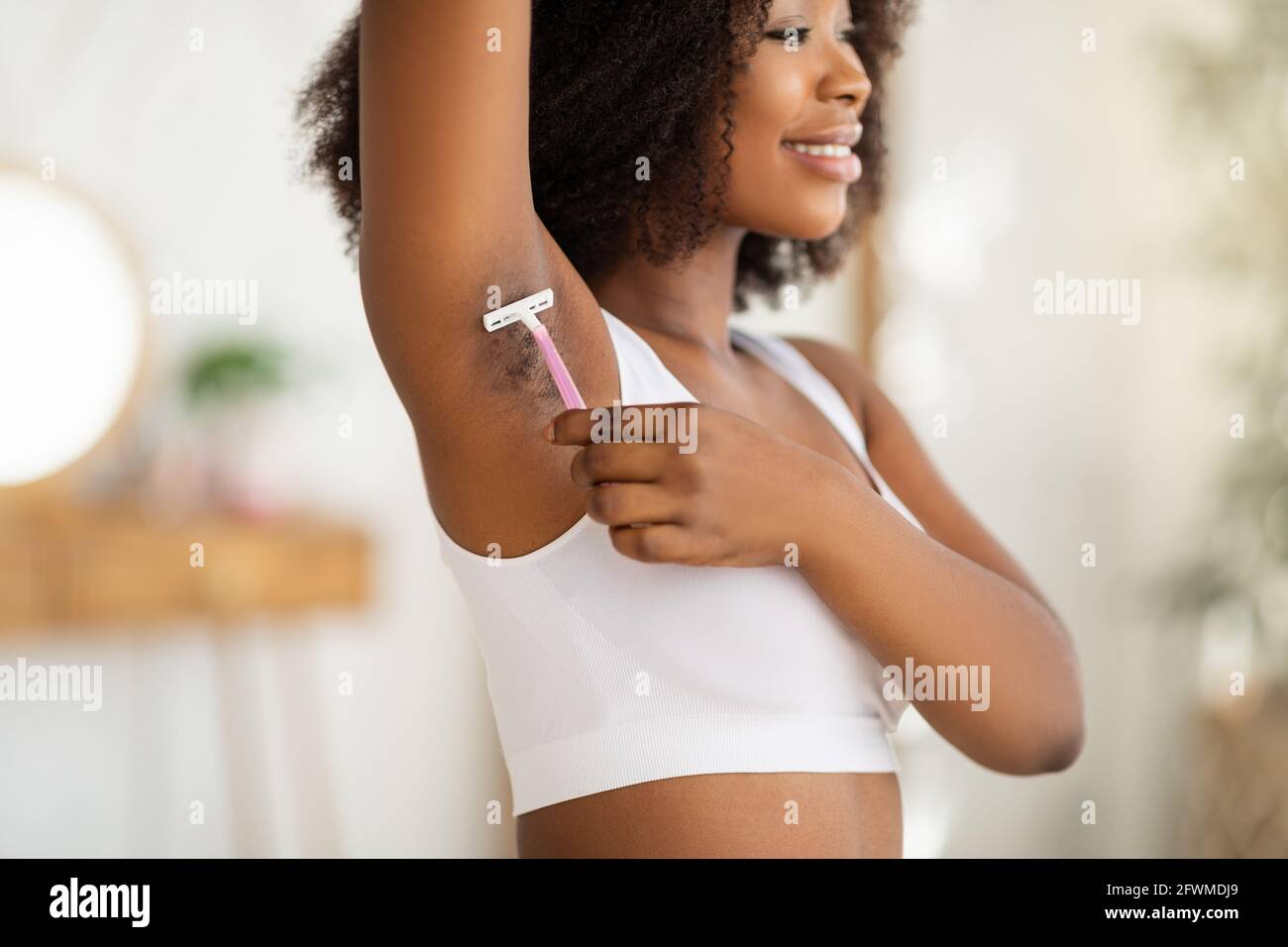 Une femme noire positive se raser l'aisselle avec un rasoir, éliminant les  poils indésirables à la maison, mise au point sélective Photo Stock - Alamy