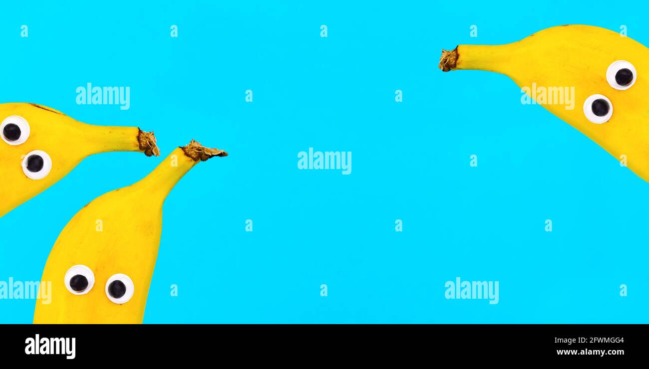 Bannière avec fruits de banane avec drôle de googly yeux sur lumineux arrière-plan bleu avec espace de copie Banque D'Images