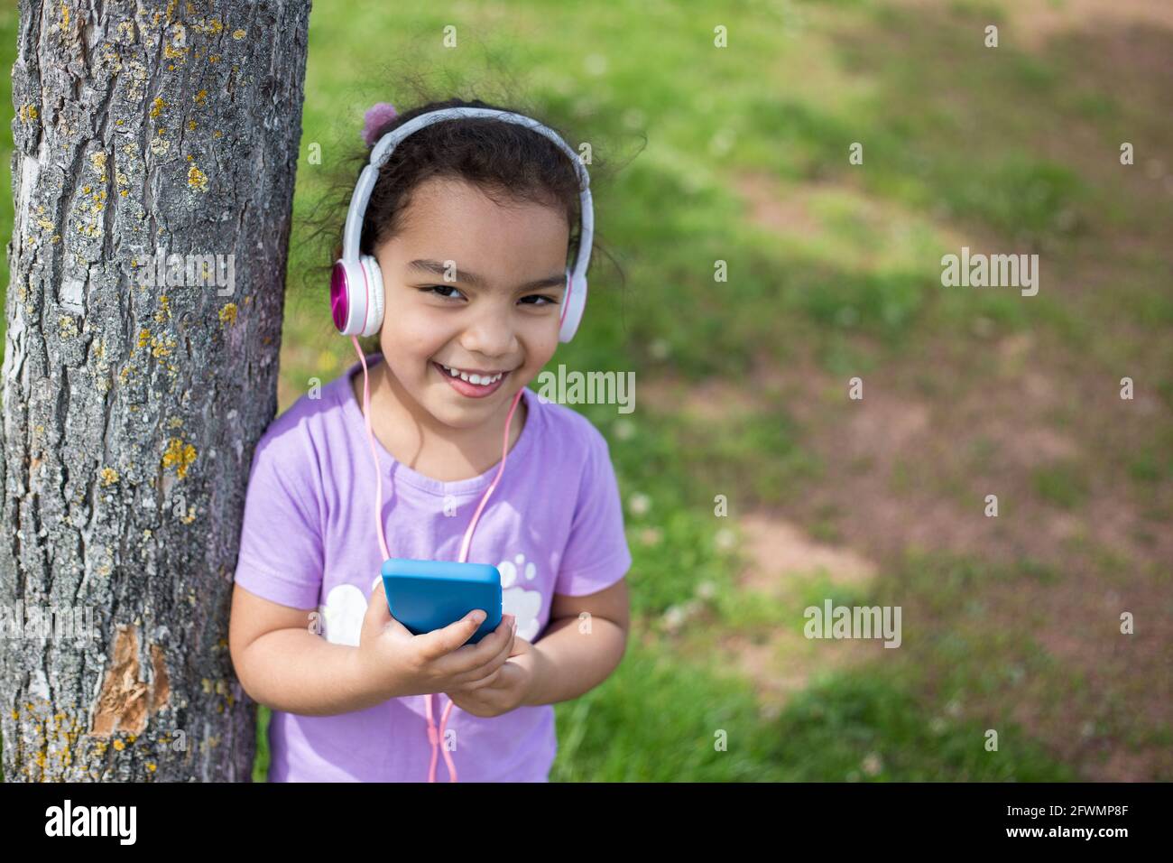 bonne fille de latina en utilisant un smartphone et un casque sur le terrain de sport Banque D'Images