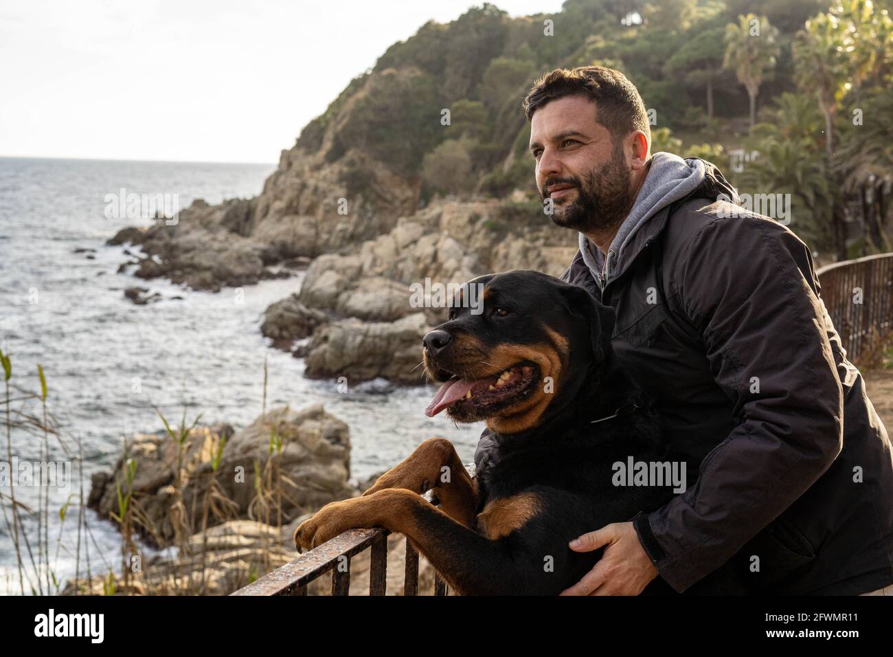 homme jouissant d'une vue sur la mer avec son chien rottweiler Banque D'Images homme jouissant d'une vue sur la mer avec son chien rottweiler Banque D'Images