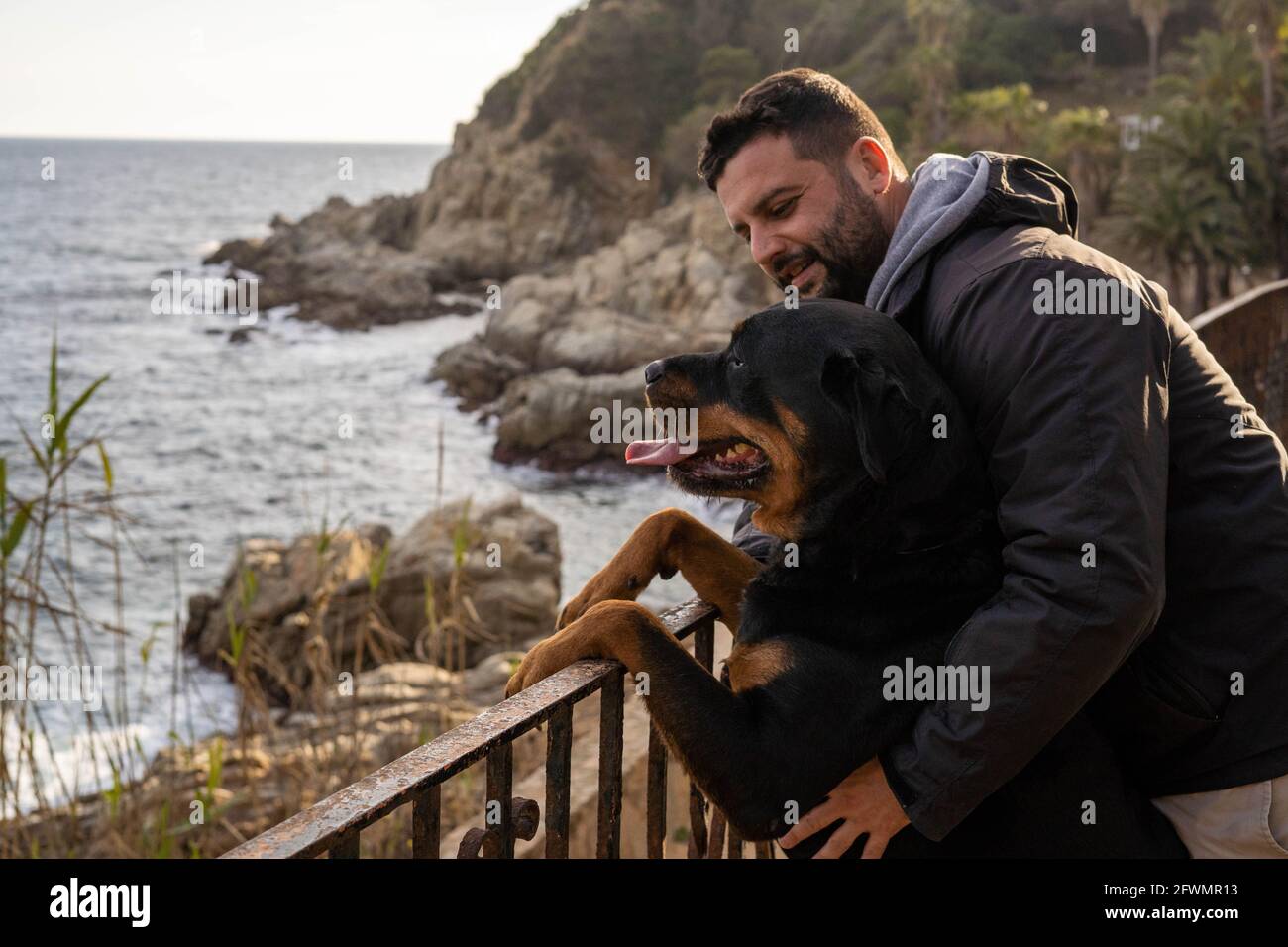 homme jouissant d'une vue sur la mer avec son chien rottweiler Banque D'Images