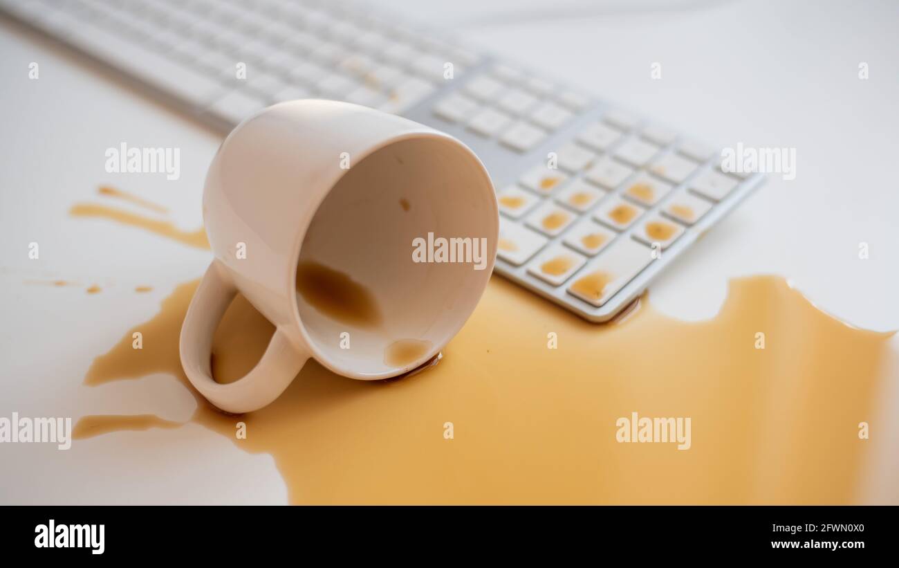 Café noir renversé sur un clavier d'ordinateur à un blanc tableau Banque D'Images Café noir renversé sur un clavier d'ordinateur à un blanc tableau Banque D'Images