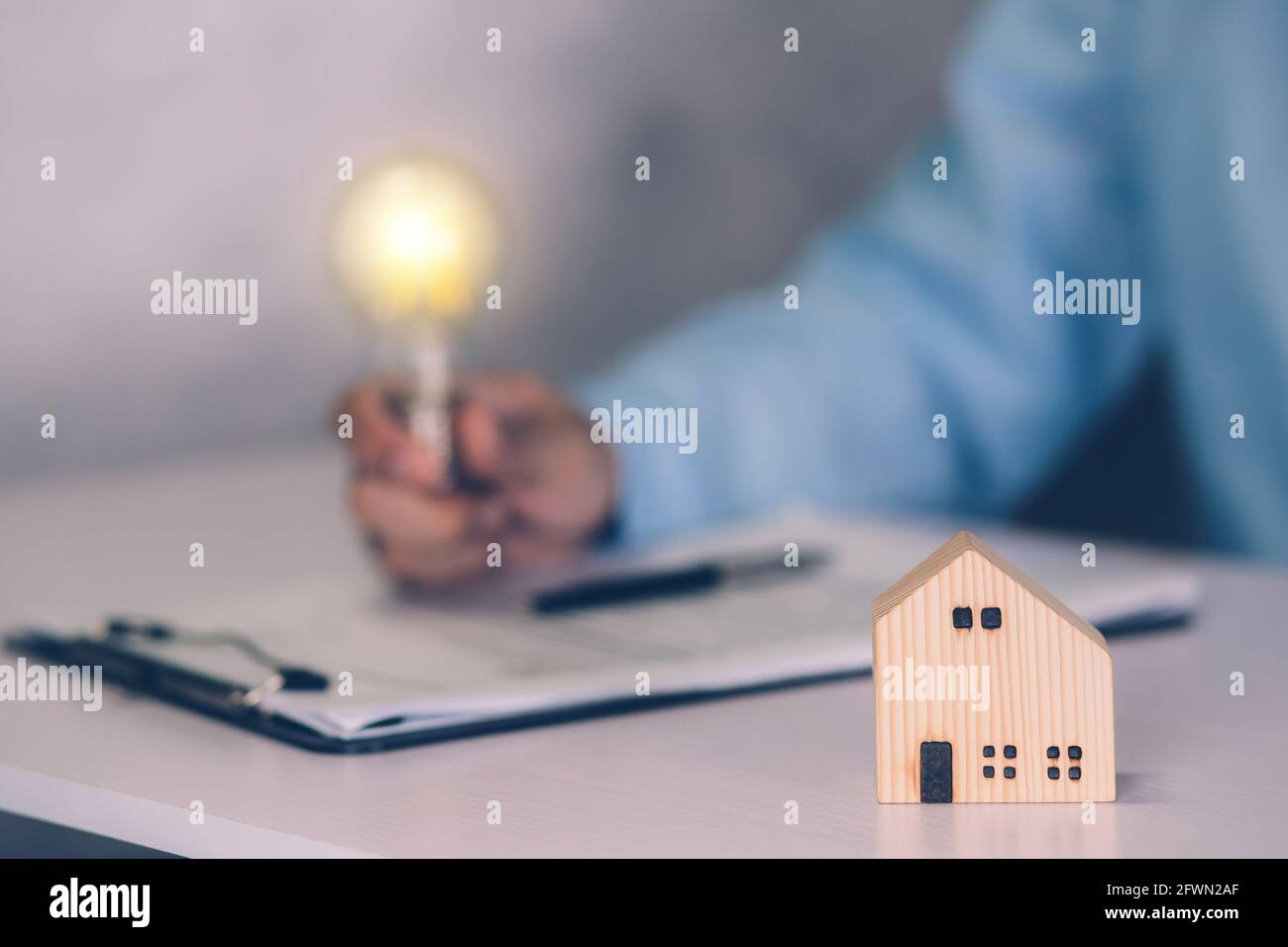 Agent immobilier tenant une ampoule et contrat accord de document immobilier sur bureau, courtier et planification d'investissement, homme d'affaires pensant ID Banque D'Images
