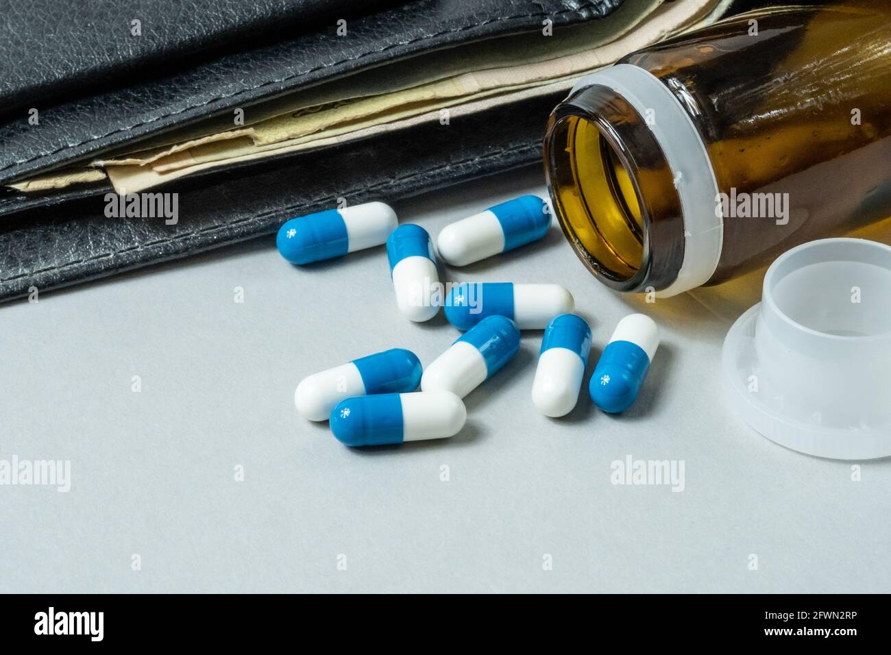 Pilules médicales dispersées sur la table contre le fond d'un portefeuille avec de l'argent. Banque D'Images