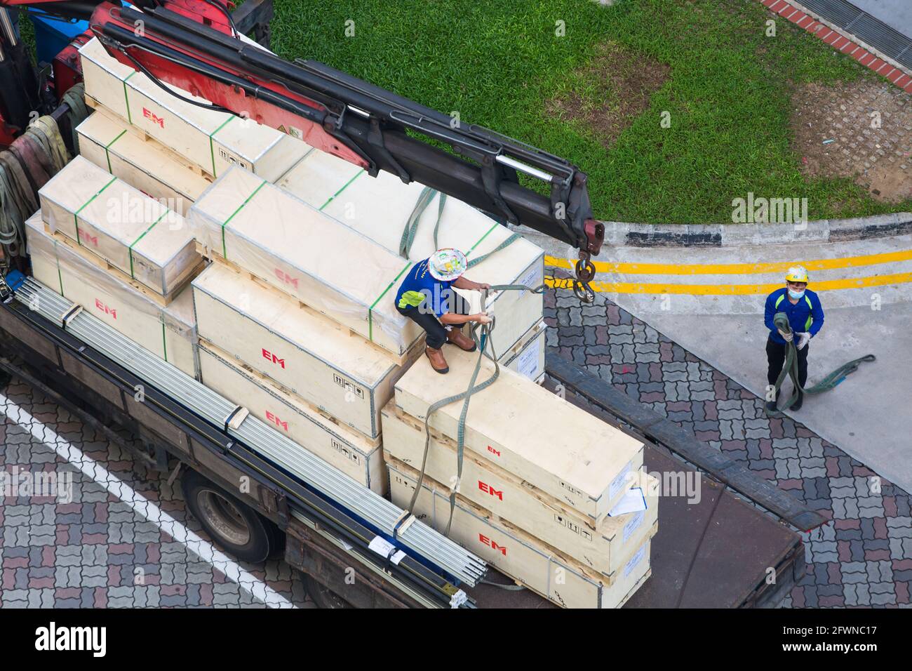 Vue aérienne d'un employé qui enchaîne soigneusement les caisses pour les déplacer et les soulever le long du sol. Banque D'Images